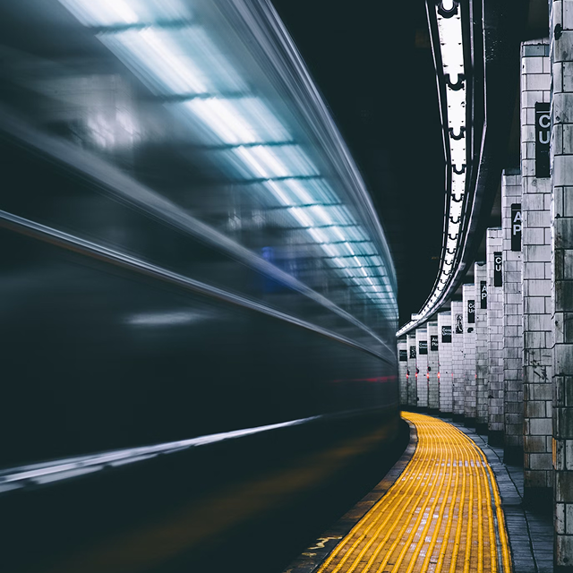 Subway train speeding through a station with yellow platform edge